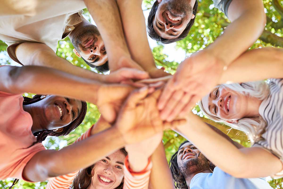 People with hands stacked to represent United Way of Central New Mexico's new name announcement and community event