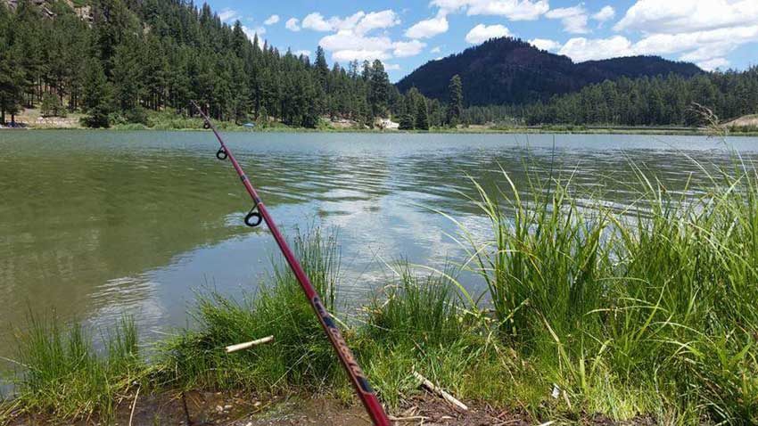 Fishing pole in foreground with line in a mountain lake at a New Mexico State Park.