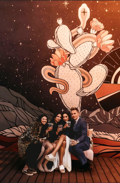 The Mystic guests in front of a mural.