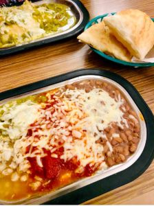 Tomasita's enchilada plate with red and green chile and sopaipillas on the side.